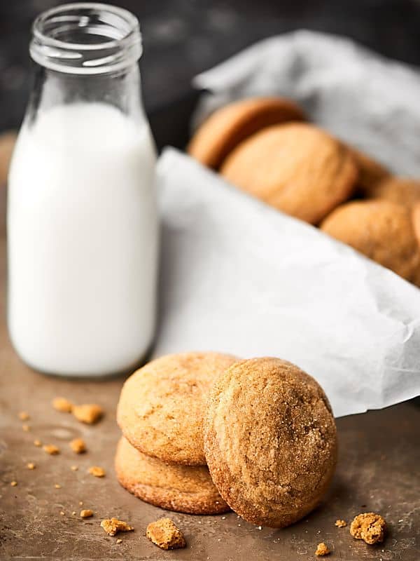 ginger cookies stacked, basket in background next to bottle of milk