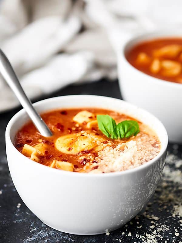 bowl of tomato tortellini soup, another in background