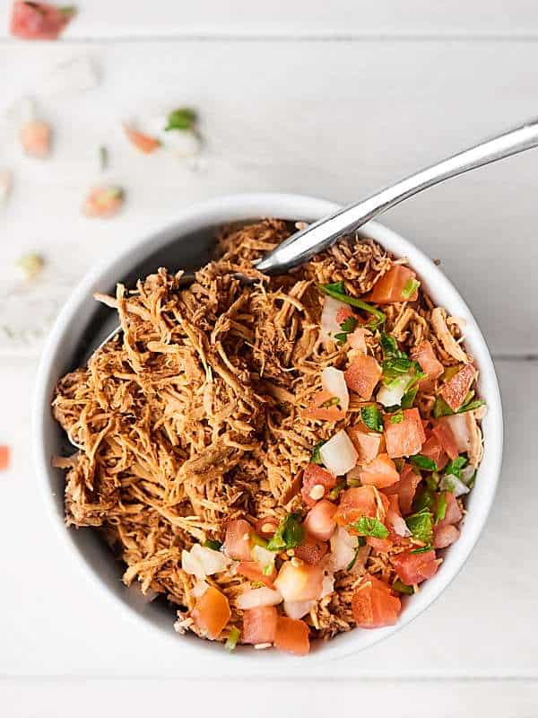 Mexican shredded chicken with pico de gallo in bowl above