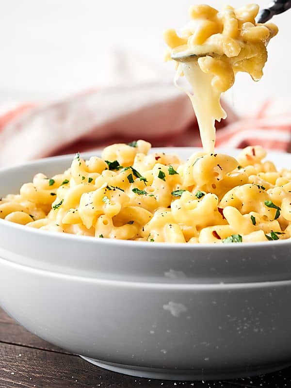 Spoonful of mac and cheese being taken out of bowl cheese pull