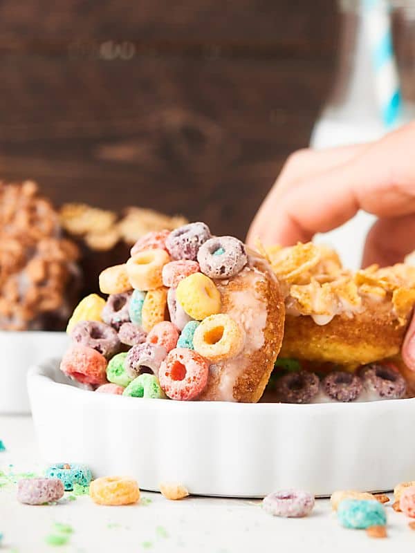plate of milk and cereal donuts, one being picked up
