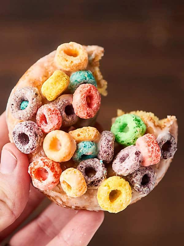 froot loop milk and cereal donut with bite out held