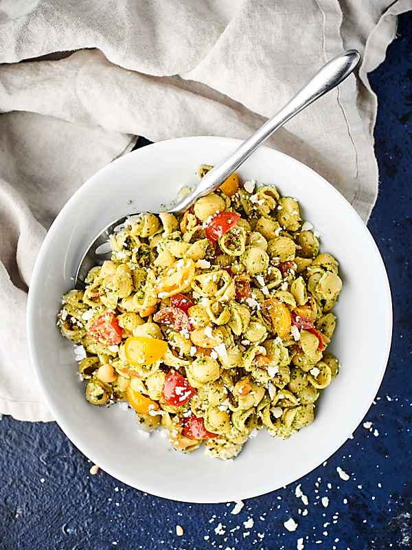 This simple Pesto Pasta Salad is loaded with pasta shells, fresh pesto, salty bacon, crumbly feta, juicy tomatoes, and crunchy cashews! showmetheyummy.com