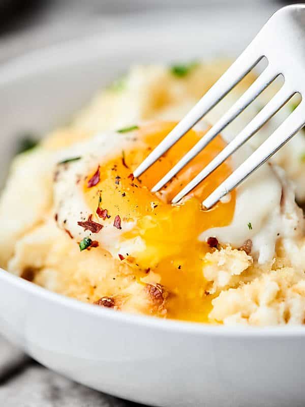 Breakfast mashed potato casserole with egg and fork closeup