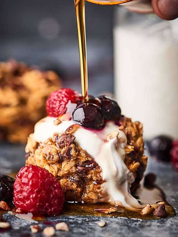 Healthy baked oatmeal cup with raspberries, blueberries, and drizzled with syrup