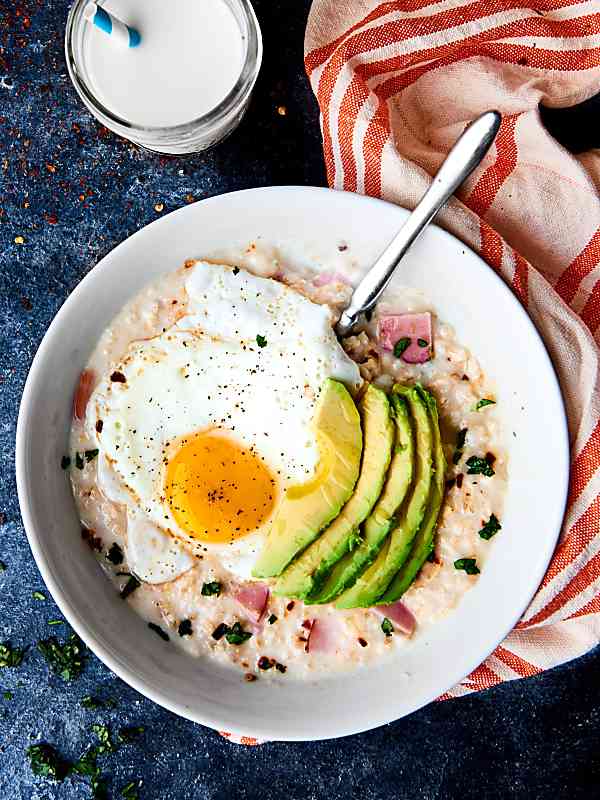 Canadian bacon and cheese overnight oats with fried egg and avocado slices above
