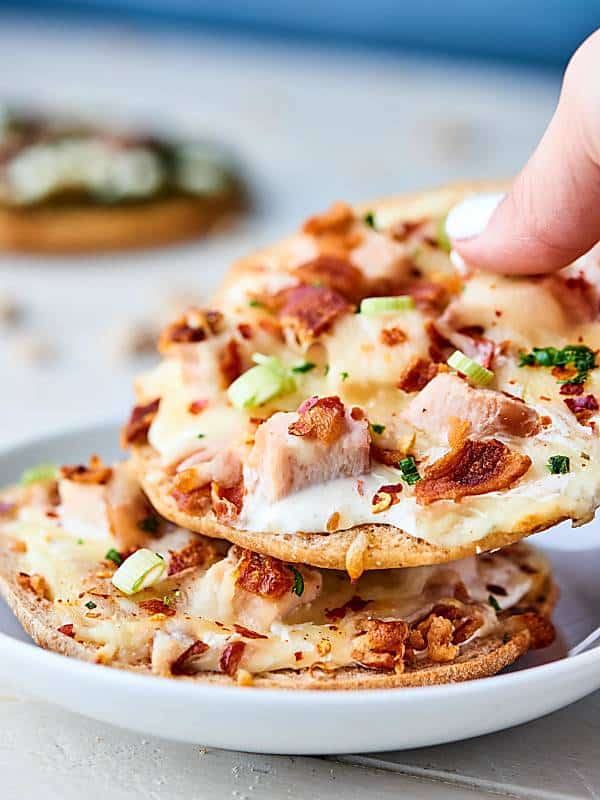 individual chicken bacon ranch pizzas on plate, one lifted
