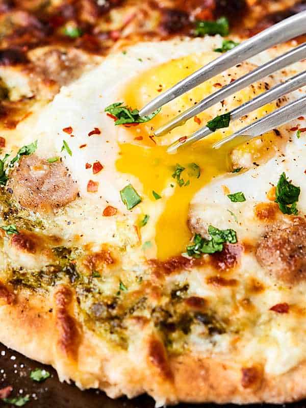 #ad These Mini Breakfast Pizzas are my latest breakfast obsession. Pita topped with fresh pesto, savory sausage, melty mozzarella, and a gooey egg! showmetheyummy.com Made in partnership w/ @jonesdairyfarm
