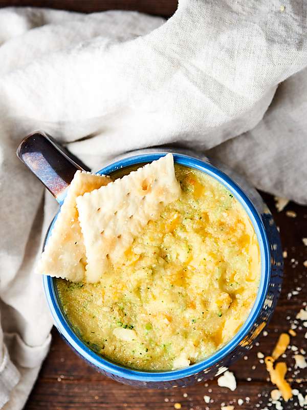 mug of broccoli cheese soup with crackers above