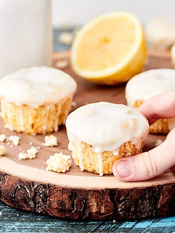Vegan lemon pound cake cupcakes on cutting board with half a lemon, one being lifted off