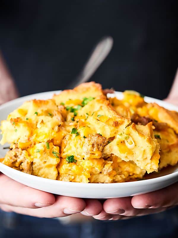 Plate with waffle sausage breakfast casserole held two hands