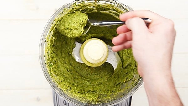 Blended avocado pesto in food processor spoonful being taken out