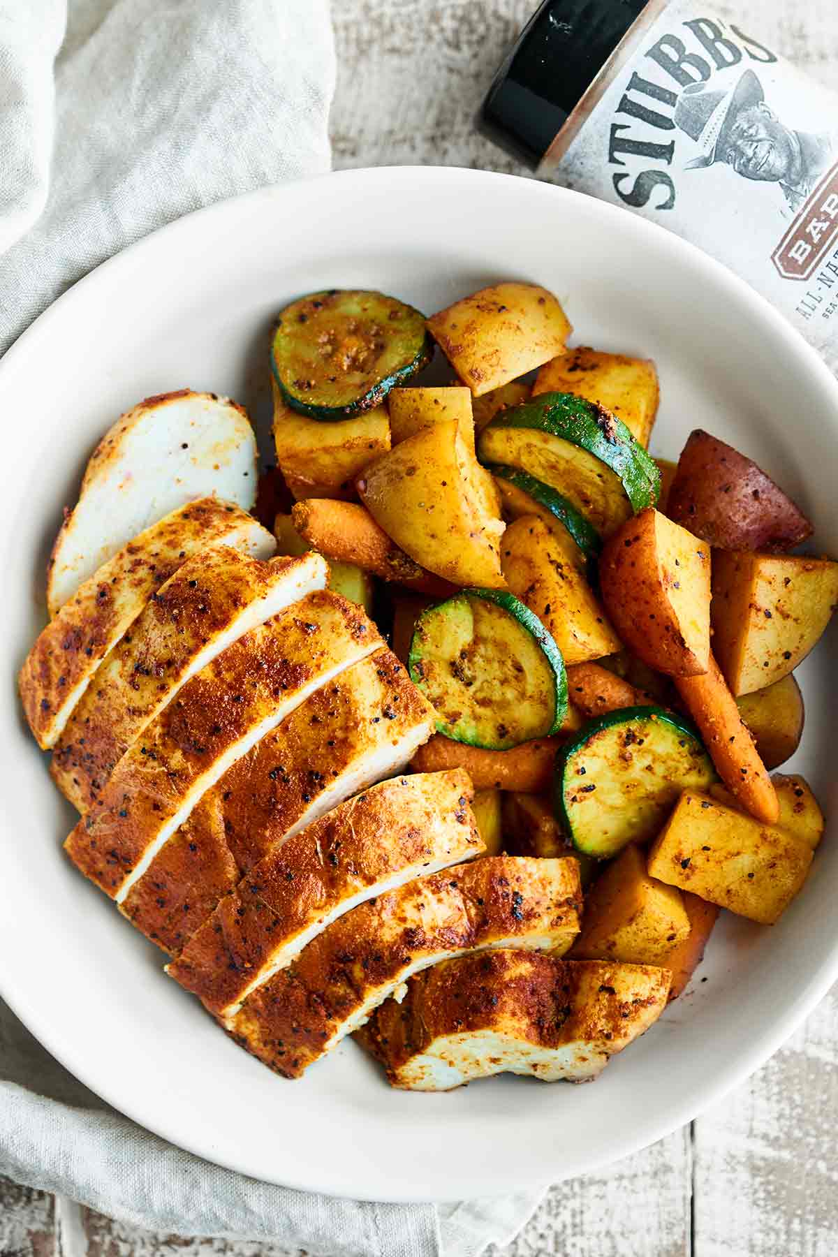 Sliced chicken and grilled veggies on plate above
