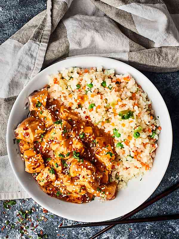 Bowl of sesame chicken with rice above
