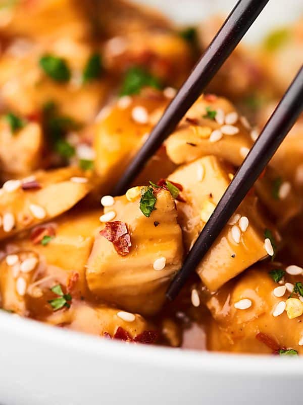 Piece of chicken being picked up with chopsticks