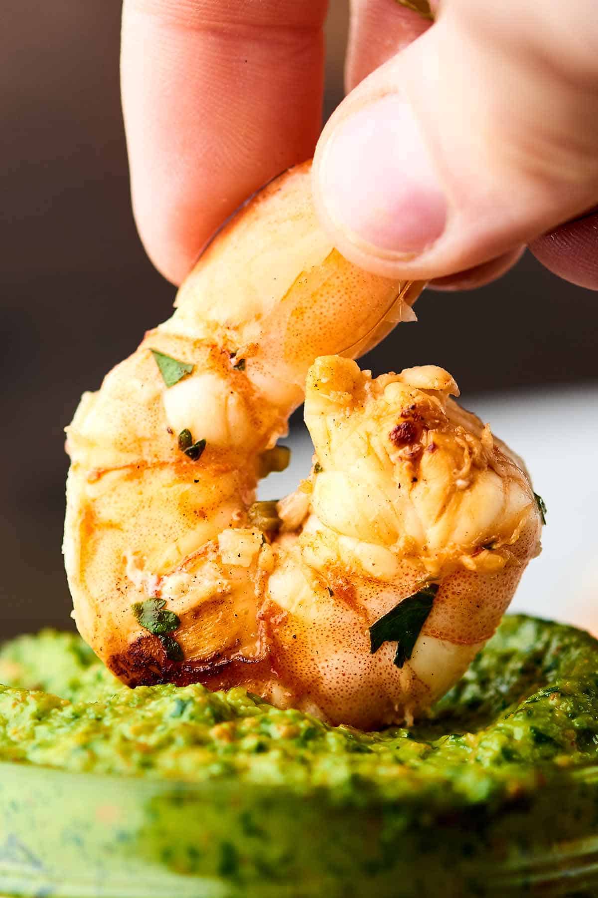 Grilled shrimp being dipped into pesto sauce