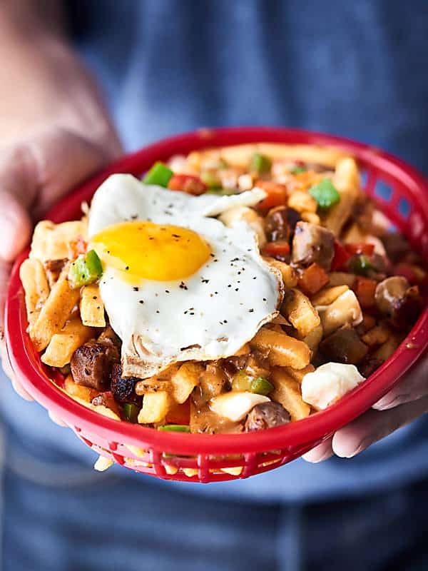 basket of breakfast sausage poutine held two hands