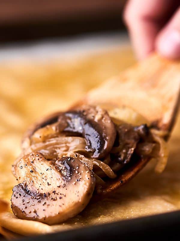 Mushrooms being scooped with wooden spoon