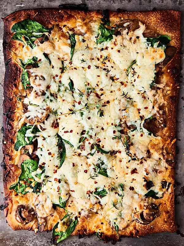 Whole, rectangular shaped caramelized onion and mushroom pizza above