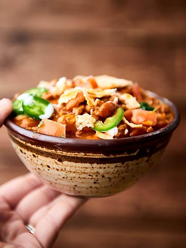 Bowl of beef chili held one hand