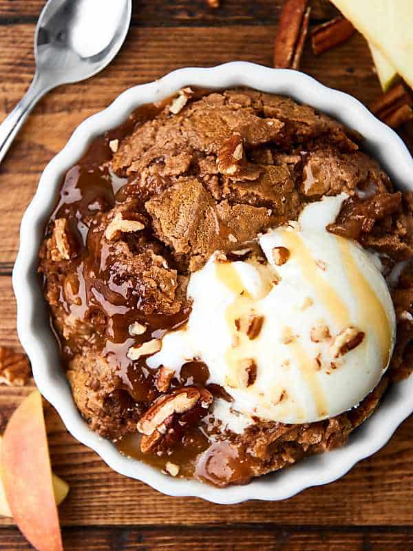 Slow cooker caramel apple dump cake in small bowl with ice cream above