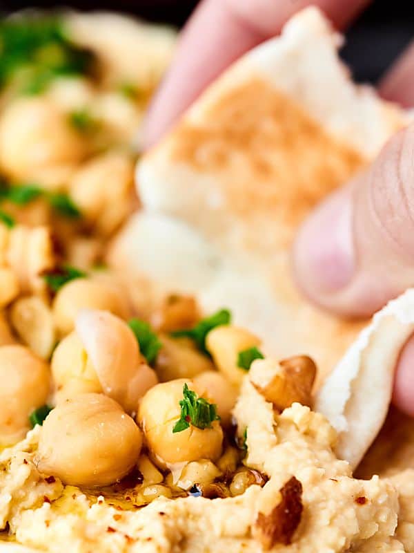 pita bread being dipped into hummus