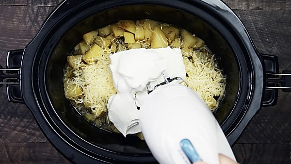 cheeses/sour cream being mixed into crockpot mashed potatoes