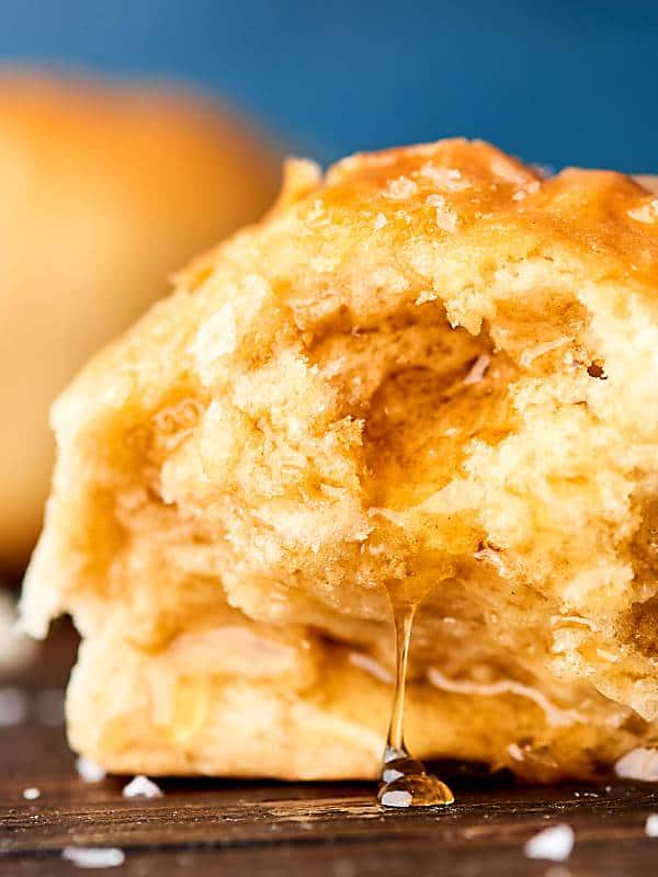 closeup of dinner roll dripping with honey