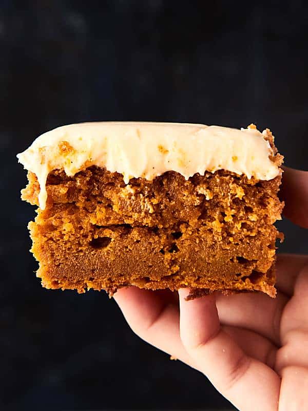 Pumpkin bar with cream cheese frosting held black background