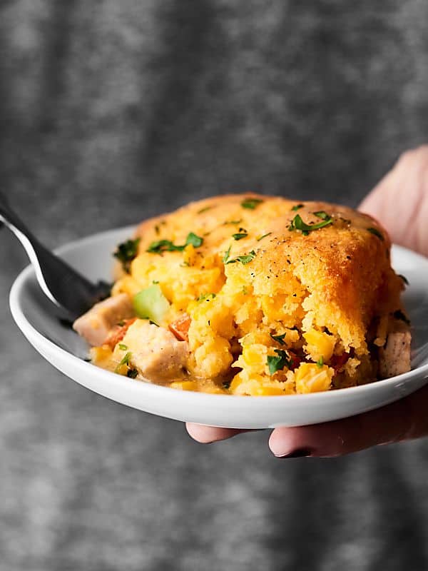 Piece of turkey cornbread casserole on plate held