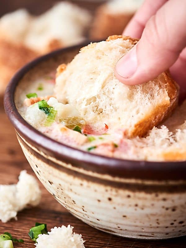 bread being dipped into bowl of potato soup