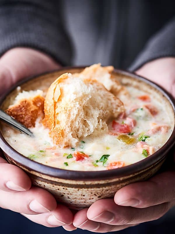 crockpot potato soup in bowl with bread held in two hands