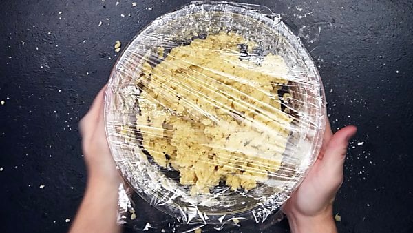 cookie dough in mixing bowl covered with saran wrap