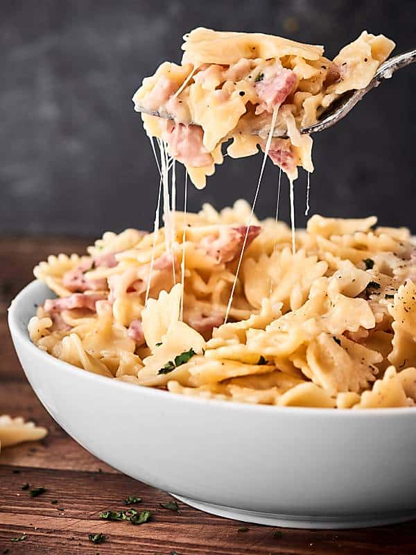 forkful being taken out of bowl of ham and cheese pasta