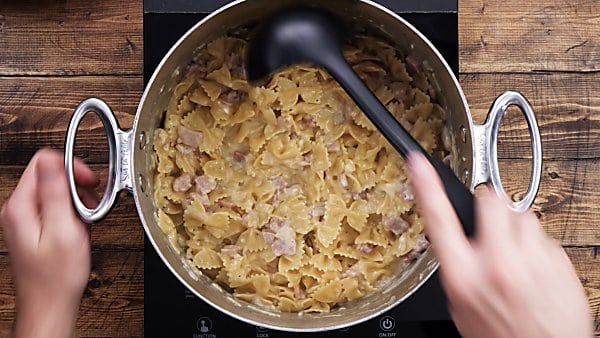 finished ham and cheese pasta in stockpot being scooped with ladle