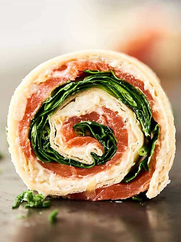 #ad These Smoked Salmon Pinwheels are perfect for easy and elegant holiday entertaining. Quick and easy to make with only four ingredients: tortillas, a lemon pepper and asiago spread, smoked salmon, and spinach! showmetheyummy.com Made in partnership w/ @laterrafina