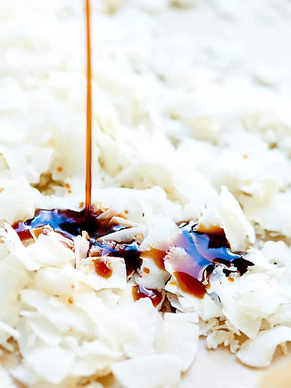 Maple syrup being drizzled into bed of coconut flakes