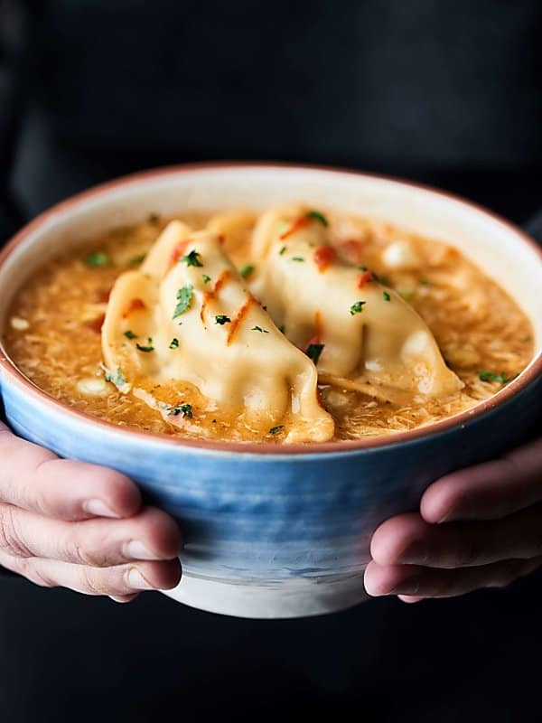 bowl of egg drop wonton soup held in two hands