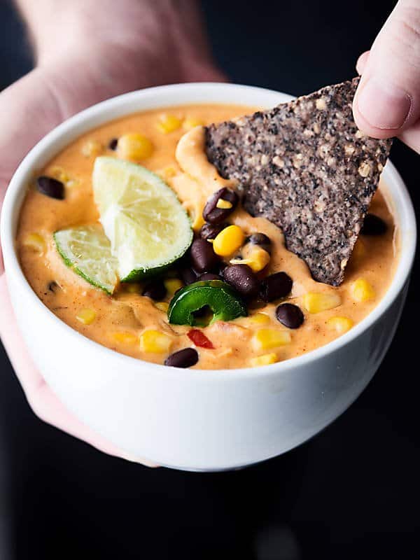 chip being dipped into bowl of loaded queso held