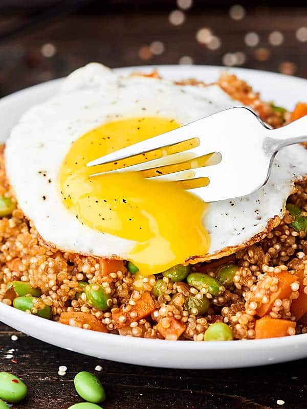 Quinoa fried rice with fork cutting into runny egg