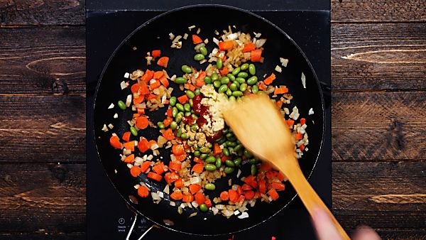 Quinoa fried rice veggie ingredients being cooked in skillet
