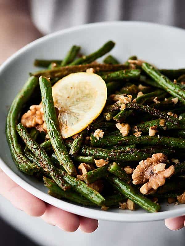 Roasted green beans on a plate held