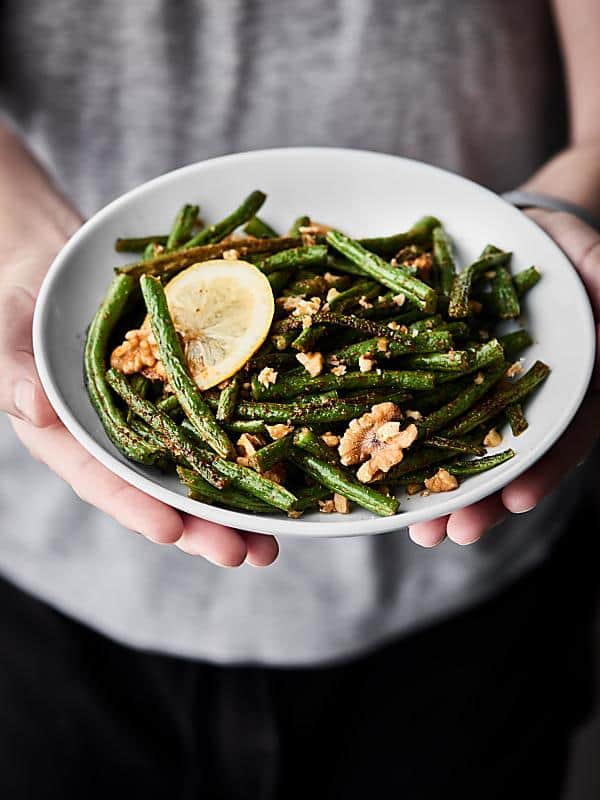 Roasted green beans on a plate held two hands