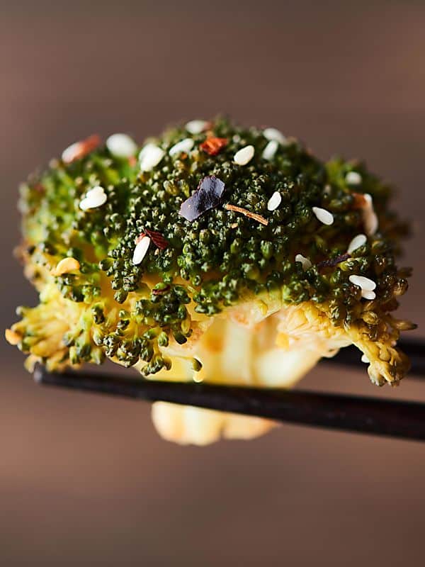 Piece of broccoli held with chopsticks