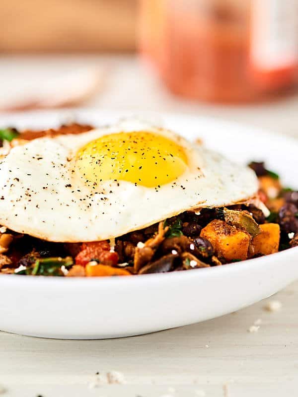 This Breakfast Burrito Bowl Recipe is full of sweet potatoes, peppers, onion, spinach, mushrooms, garlic, black beans, and spices. Topped with a fried egg, salsa, and greek yogurt! Healthy. Meatless. Gluten Free. Perfect for meal prep! Can be vegan! showmetheyummy.com #breakfast #healthy #burrito