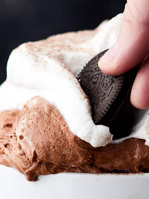 oreo being dipped into bowl of hot chocolate cheesecake dip