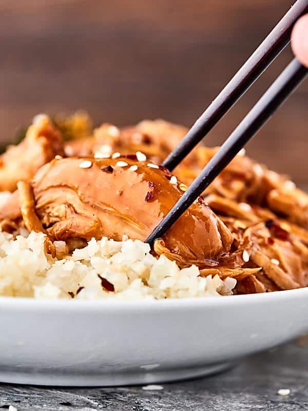 Piece of orange chicken being picked up with chopsticks