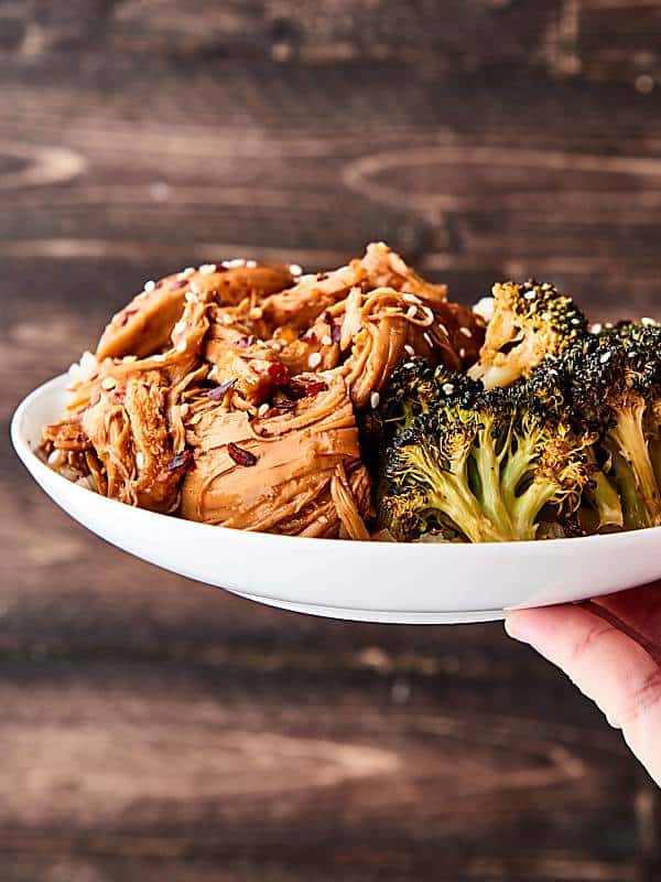 Plate of orange chicken and broccoli held