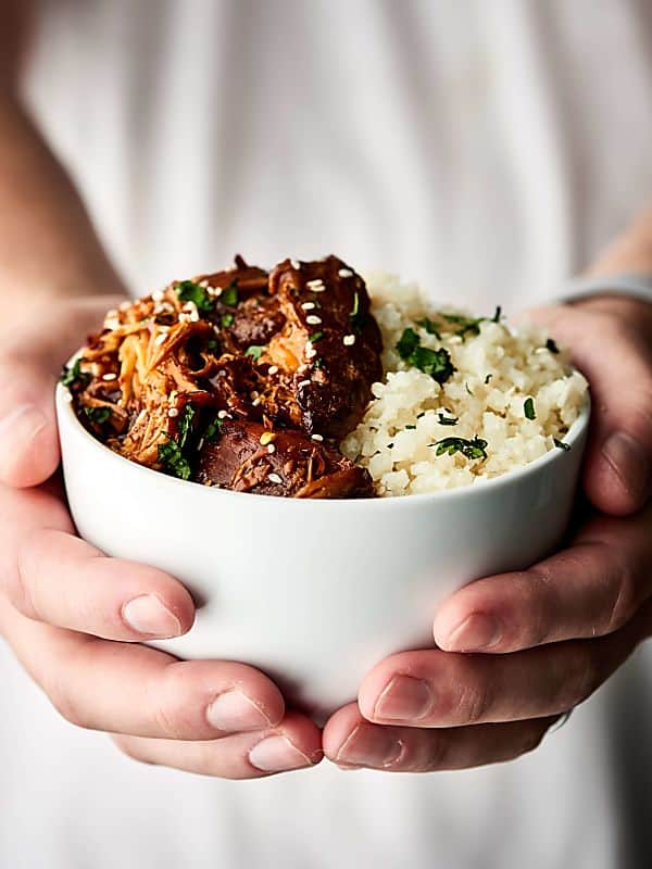 Crockpot chicken teriyaki in a bowl held in two hands