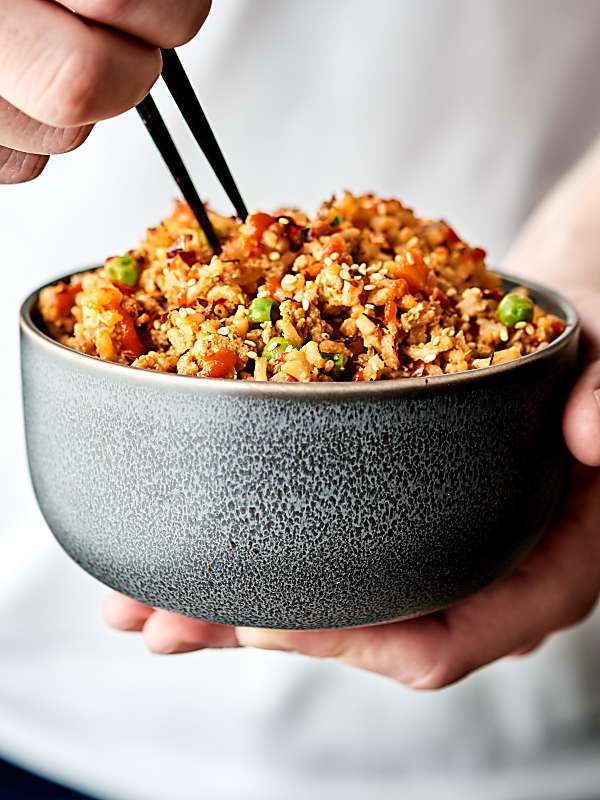 Bowl of fried rice held with chopsticks